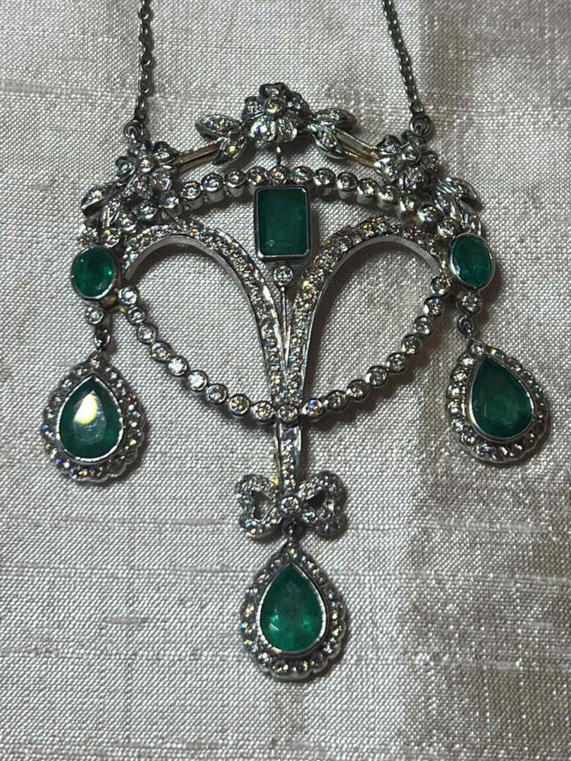 Vintage silver brooch with green gemstones in an ornate design.