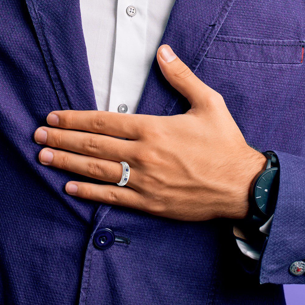 Man in a blue suit with an engagement ring on his hand.