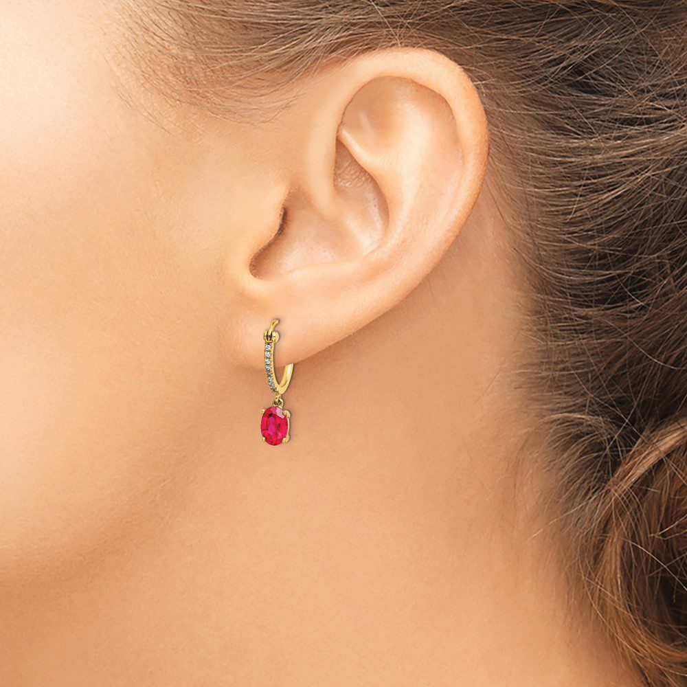 Close-up of an ear wearing a gold hoop earring with a red heart charm.