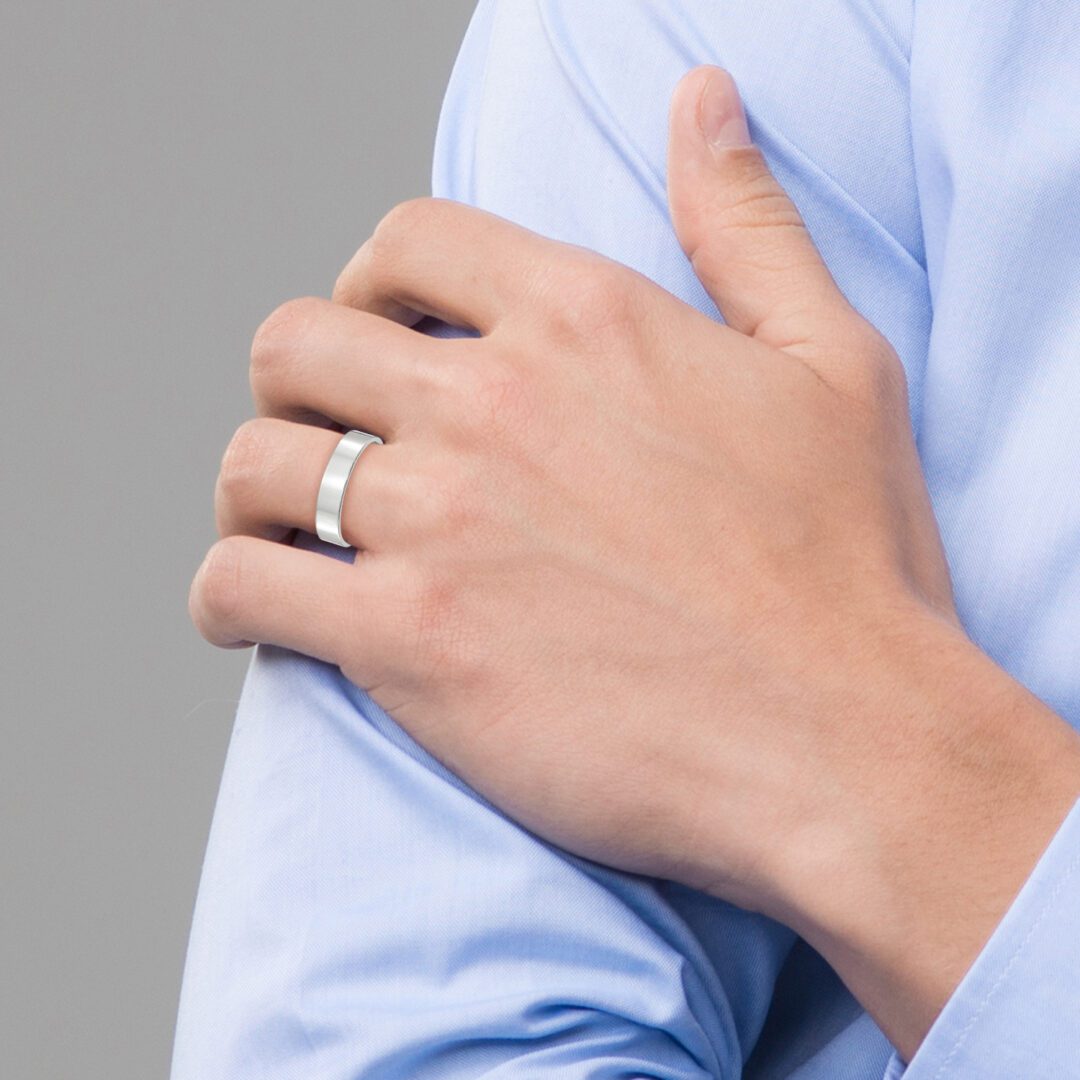 Hand with a silver ring resting on a blue shirt sleeve.