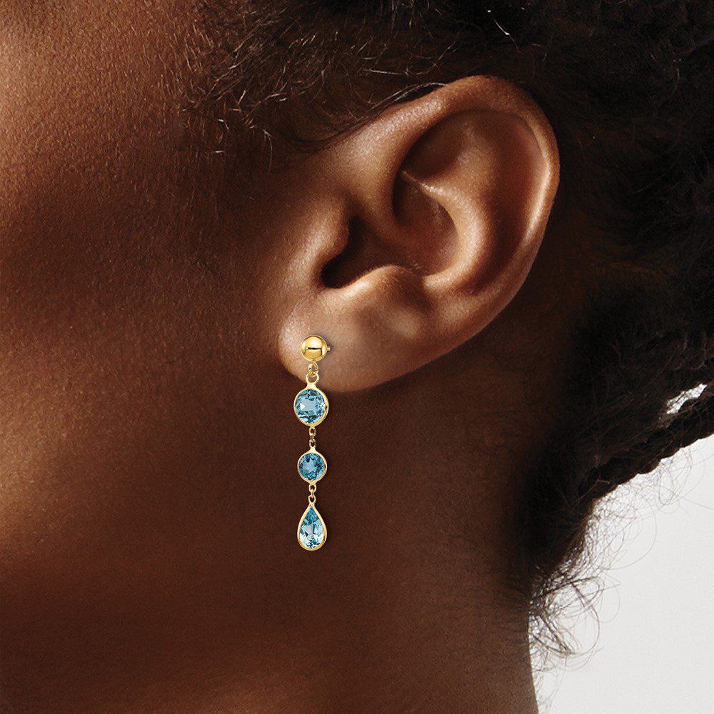 Elegant gold earrings with blue gemstones dangle gracefully.